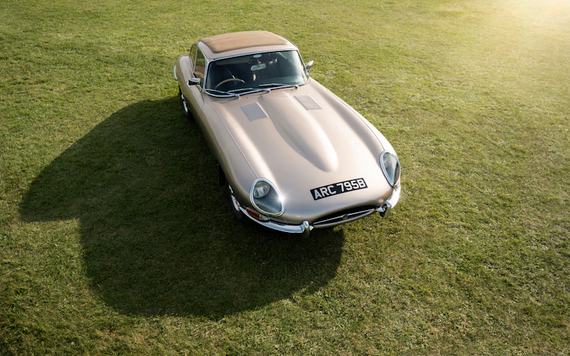 A silver Jaguar E-Type coupe on a grass lawn, seen from above