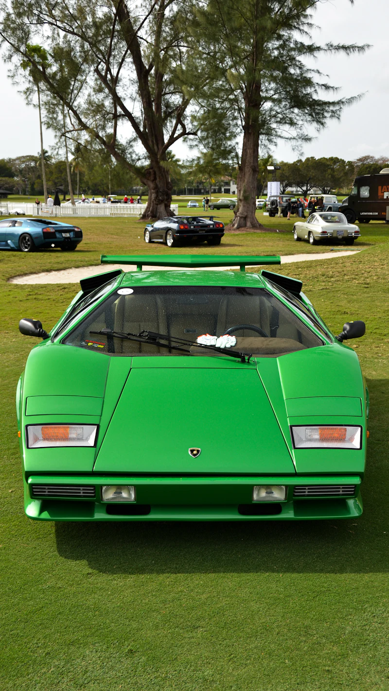 A green Lamborghini Countach with a rear wing, on the lawn at a concours