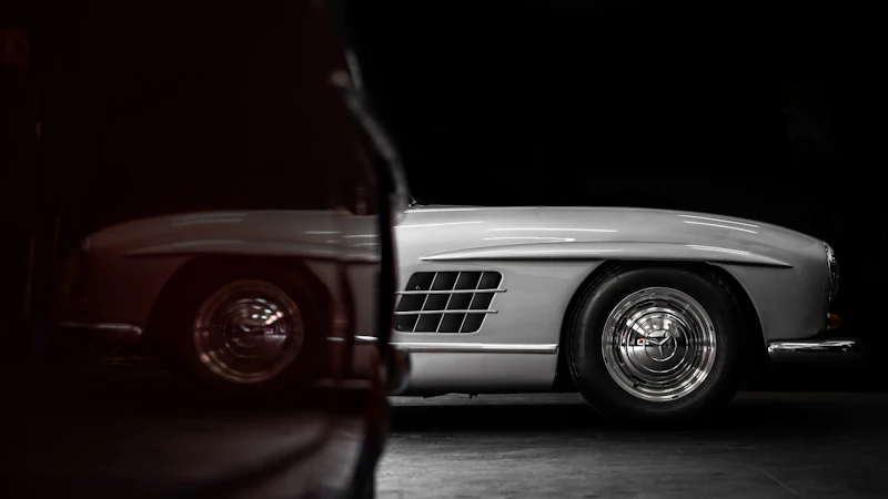 The side of a silver Mercedes-Benz 300 SL Gullwing in a dark studio, showing its wing vents