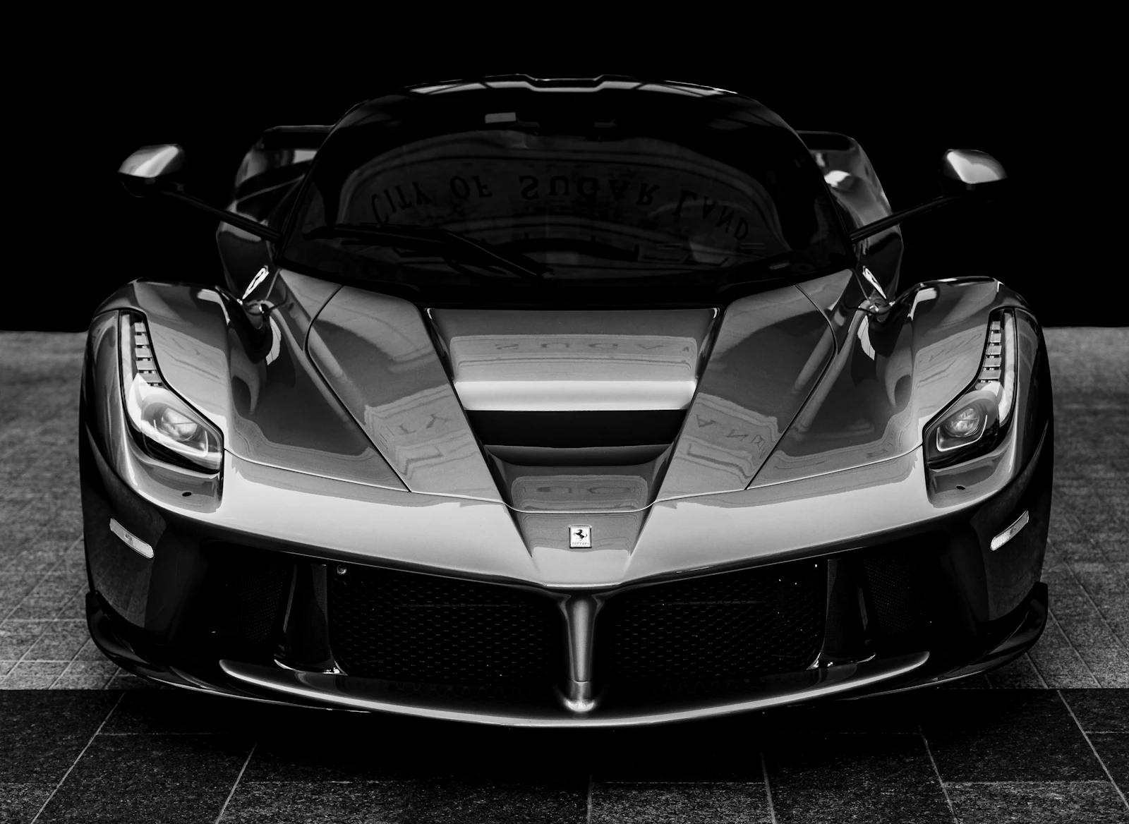 A Ferrari LaFerrari seen head-on in black and white, in a dark room